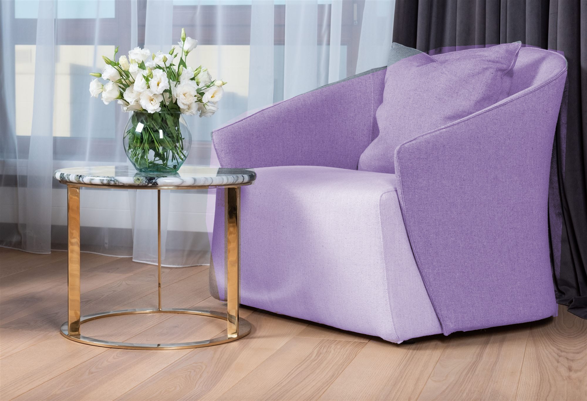 An empty lavender armchair beside a table of white flowers