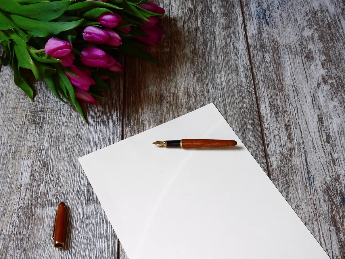 Purple tulips beside a blank page and a pen