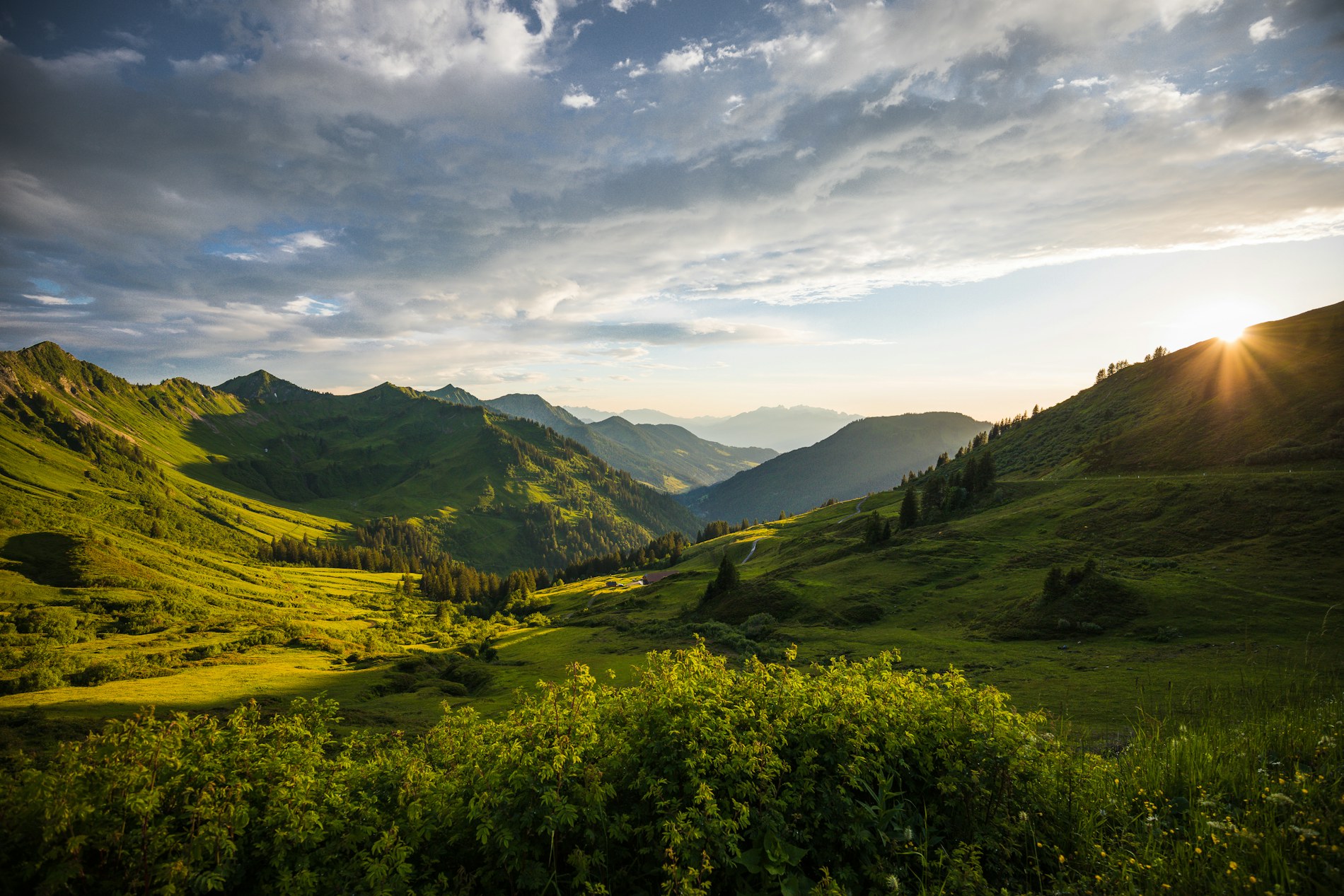 Sunlight breaking over a green valley at dawn